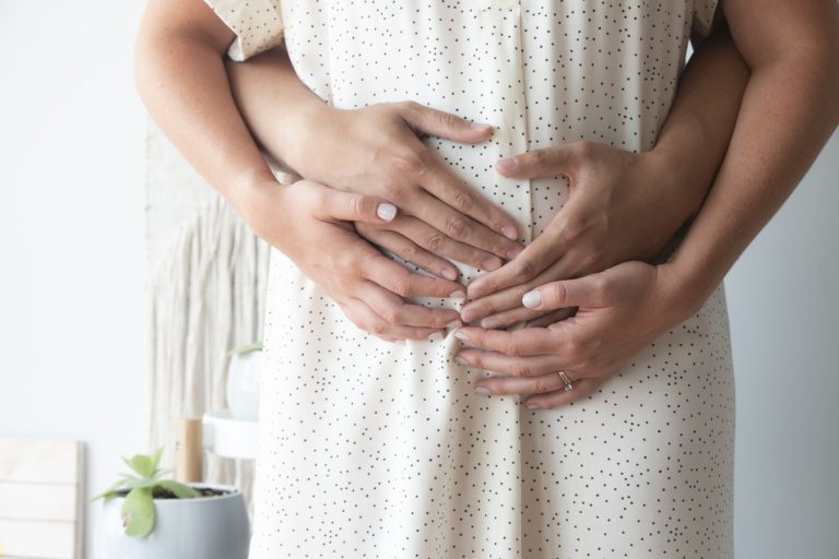 mãos tocando a barriga de uma mulher grávida